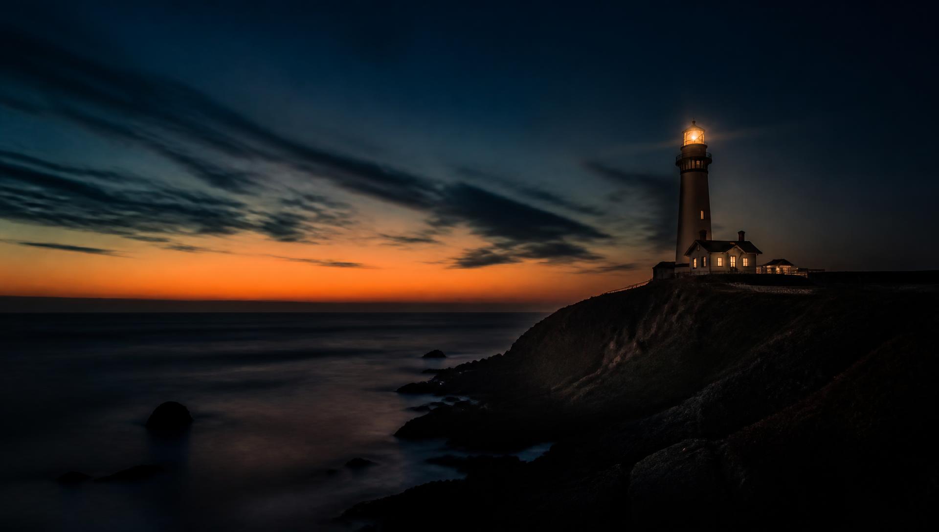 A lighthouse on a rocky headland at dusk